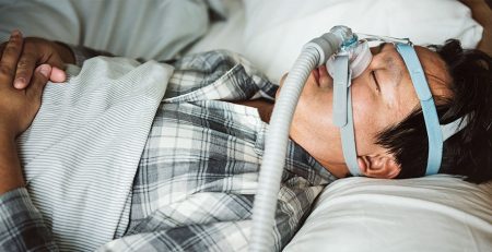 Hombre durmiendo con una correa para el mentón para el tratamiento de la apnea del sueño