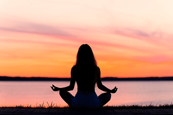 Mujer meditando al atardecer